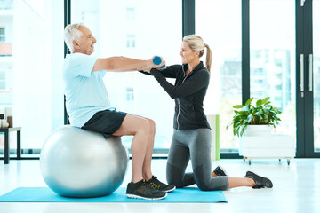 Fototapeta premium Working on all those stiff muscles. Shot of a physiotherapists helping her senior patient with his exercises in a fitness center.