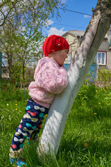little girl leaned against a tree,In the spring, a child girl leaned against a sloping tree in an...