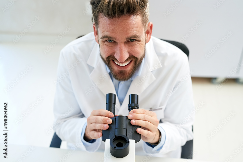 Poster Clinical trials are an essential part of advancing medical science. Portrait of a male scientist using a microscope in a lab.
