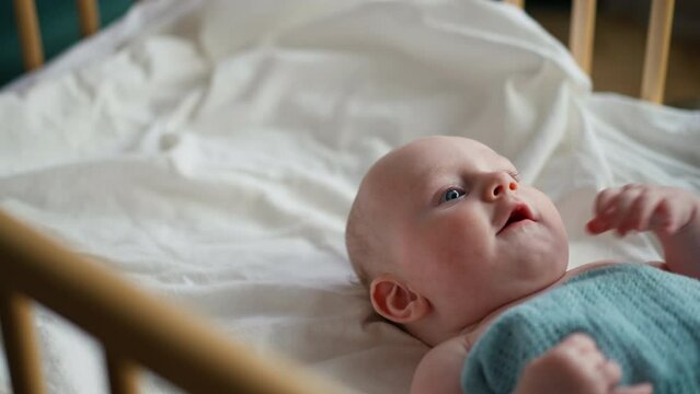 Baby toddler laying on the blue blanket, baby crying.