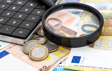 Calculator, magnifying glass with euro bills and coins. Close up.