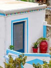 A colorful house front, with decorative stripe and blue door, Olympos village, Karpathos island, Greece.