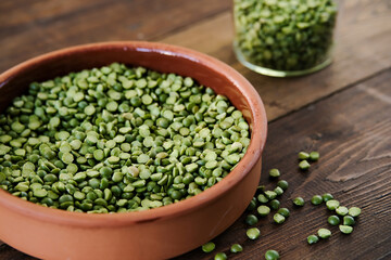 Dry green peas in a bowl. Split green peas. Peas on a wooden background. Side view. Lettering green dry peas.