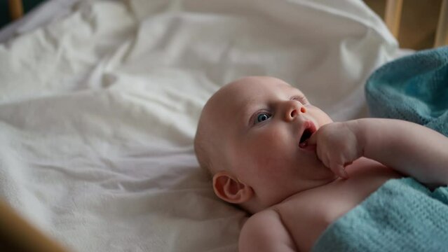 Little cute causian baby boy, boy asks to eat. he puts his hand in his mouth