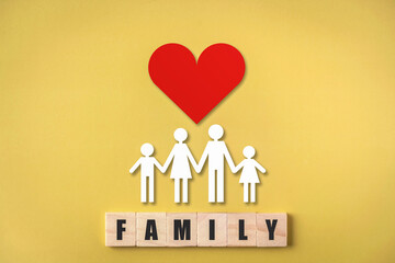 Wooden cube with family text , Family figures with red heart on yellow background , Medical care and health insurance concept.