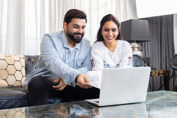 Indian couple accounting, calculating bills, discussing planning budget together using online banking services. - Powered by Adobe