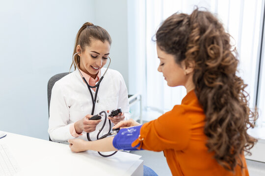 Nurse measuring blood pressure of a woman patient during an examination in the clinic. Doctor checking patient arterial blood pressure. Health care.