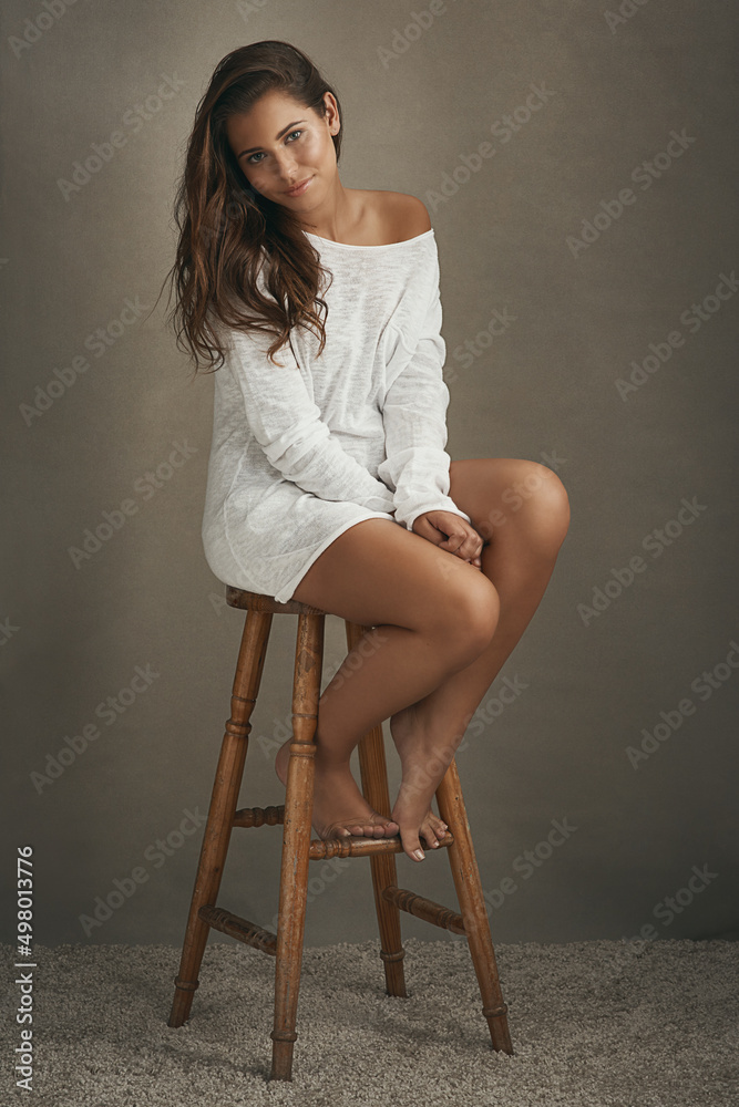 Poster Shes got nothing to be shy about. Portrait of a beautiful young woman sitting on a stool against a brown background in studio.