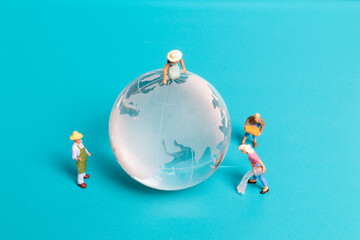 Miniature people cleaning crystal globe on blue background , World environment day concept
