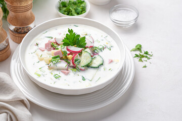 Summer vegetable soup okroshka with fresh herbs on a white background.