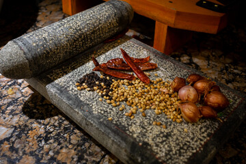 Spices, masalas like black pepper, dried chilly, coriander, onions on grinding stone or Sil Batta used in ancient times, traditional cooking, taste, ayurvedic, healthy,  Indian, earthenware concept
