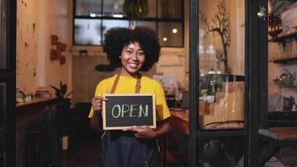 Young Female manager in restaurant with digital tablet or notebookWoman coffee shop owner with face mask hold open sign .Small business concept. - Powered by Adobe