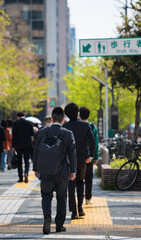 オフィス街の新緑と通勤の人々の姿