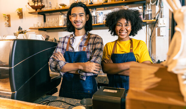 Young  Couple Asian Man And African Woman Manager In Restaurant With Digital Tablet Or NotebookWoman Coffee Shop Owner With Face Mask Hold Open Sign .Small Business Concept.