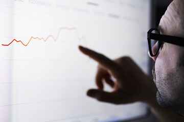 A businessman is looking at a graph on a monitor. An exchange broker evaluates stock market trends....