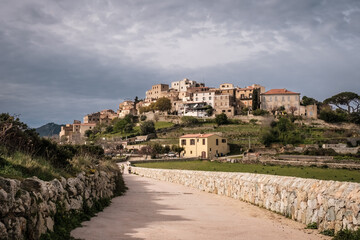 Fototapeta na wymiar Track leading towards the hilltop village of Sant'Antonino in the Balagne region of Corsica with snow capped mountains in the distance