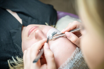 Obraz na płótnie Canvas Eyelash extension procedure in beauty salon. Lashes close up. Concept spa lash. 