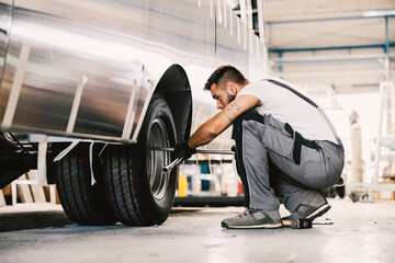 Fototapeta na wymiar An auto-mechanic fixing tire on a vehicle at workshop.
