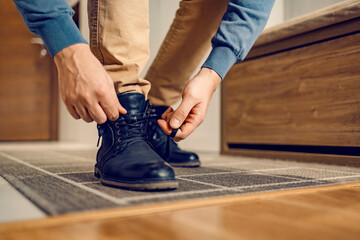 A man tying shoelace on leather shoes at home. - obrazy, fototapety, plakaty