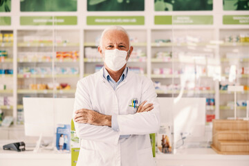 A proud senior pharmacy worker posing with face mask.