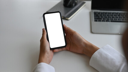 Top view close up of hands leaning to the table in the office holding a smartphone with a blank  white screen, for business and technology concept.