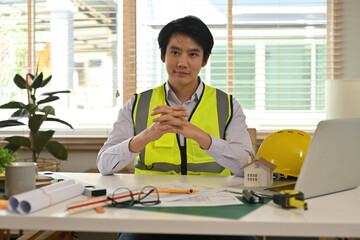 A portrait of a foreman engineer or architecture sitting in the office, looking at the camera with confidence, for engineering, architect, business, safety and technology concept.