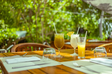 Luxury resort hotel, outdoor restaurant under palm trees and sky, tropical island cafe, tables, food, cocktails. Summer vacation or holiday, family travel. Palm trees, infinity pool, cocktails, relax