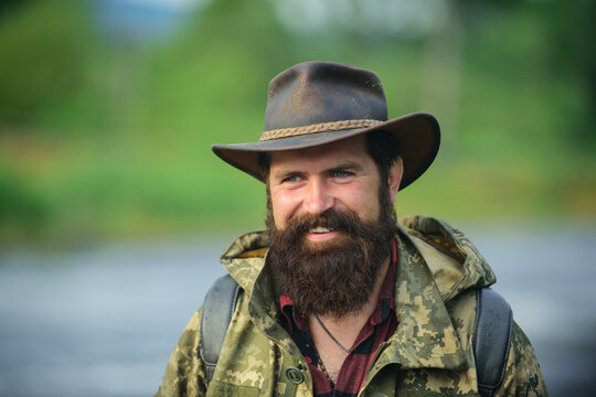 Portrait Of Traveller Bearded Man In Cowboy Hat. Close Up Portrait Of Happy Middle Aged Smiling Man In A Countryside.