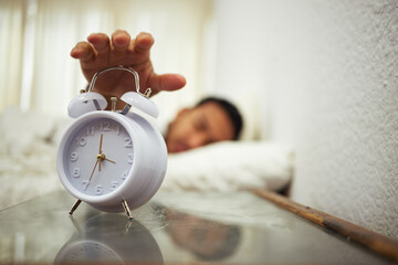 Five more minutes. Shot of a man reaching for his alarm clock.