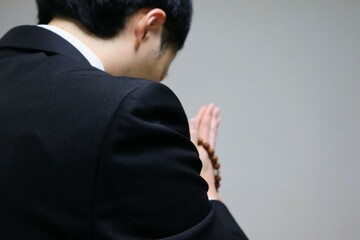 葬儀で祈る日本人男性