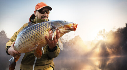Fishing background. Young man hold big carp in his hands. - 498028312