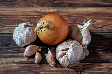 Fresh garlic bulbs and a garlic press on an old wooden board and a burlap backing.