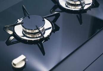 closeup of expensive black gas stove with glass and metal finish