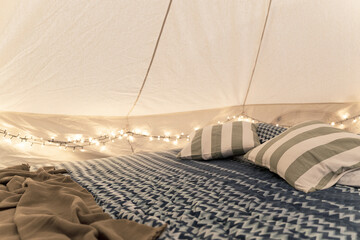 glamping tent interior detail with bed pillows and intimate lights - obrazy, fototapety, plakaty