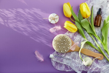 Spring beauty SPA treatment complete hygiene accessories, essence oil, massage brush, bath bomb, sponges on purple background. Natural shadows, copy space