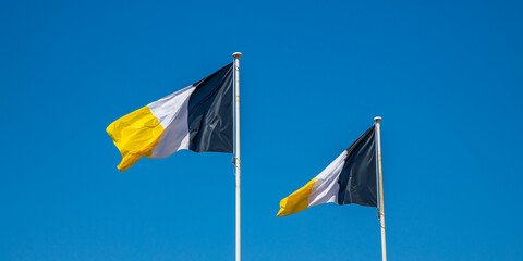 Flags of Arcachon, of yellow white and black color, waving in the air on a summer day in France