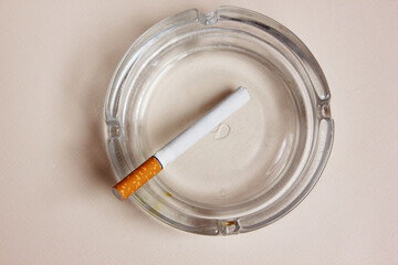 cigarette and an ashtray on white background. the cigarette is on the ashtray. Yellow filter. Harm to health. It a bad habit. The vision of world without tobacco, tobacco and lung health. Lung cancer.