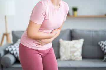 Stomach ache, symptoms of gastritis or pancreatitis, woman with abdominal pain at home interior - obrazy, fototapety, plakaty
