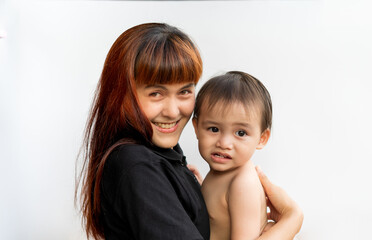 Happy mother with her baby on isolated white background. Mom wearing black shirt holding her son and smiling merrily. Young attractive happy mother smiling hugging looking at her littel baby.