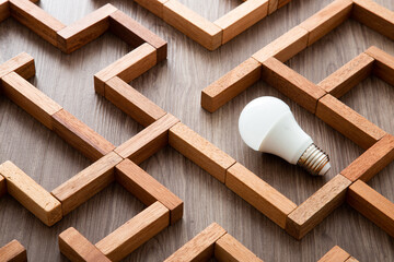 Light bulb in the maze game built by wood blocks, finding the right way to the success, idea concept