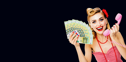 Photo of happy excited woman holding money euro cash banknotes, talking on phone, dressed in pinup...