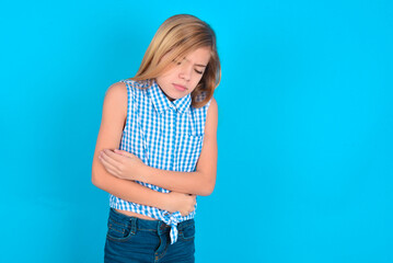 little kid girl with glasses wearing plaid shirt over blue background  suffering from strong...