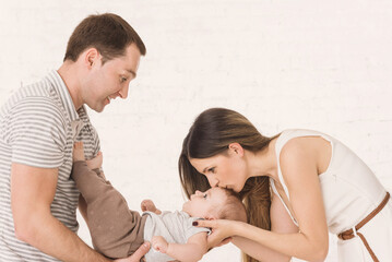 Happy family with little baby boy play with little son at home on the white brick wall background