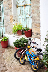 Fototapeta na wymiar Child and adult bicycle in front of a traditional stone house facade in a Greek village
