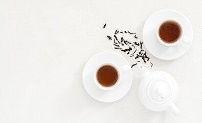 two white cups of black tea, next to a white teapot for brewing a drink, white non-uniform background, flat lay, flat lay, flat lay, top view, copy space, mockup