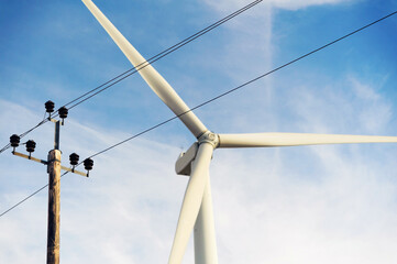Power electric pole line with cables and wind turbine on the background transmits generated free...