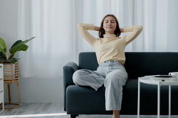 woman stretching relax. She is relaxing on the sofa in the living room on vacation. She does yoga poses to relax after a hard day's work. The idea of taking a break from hard work.