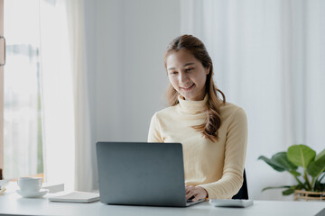 Fototapeta premium Asian woman studying online on laptop and taking notes in a notebook, She is a university student, The concept of online learning due to the COVID-19 outbreak to prevent an outbreak in the classroom.