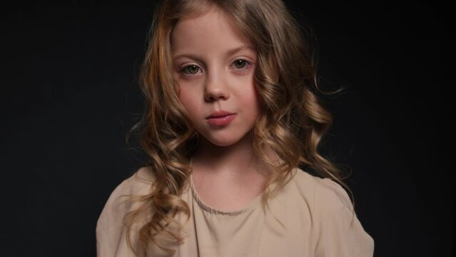 Portrait of a little sad girl on a dark background.