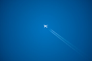 high altitude contrails from a twin engine jet aircraft in a clear blue sky - obrazy, fototapety, plakaty